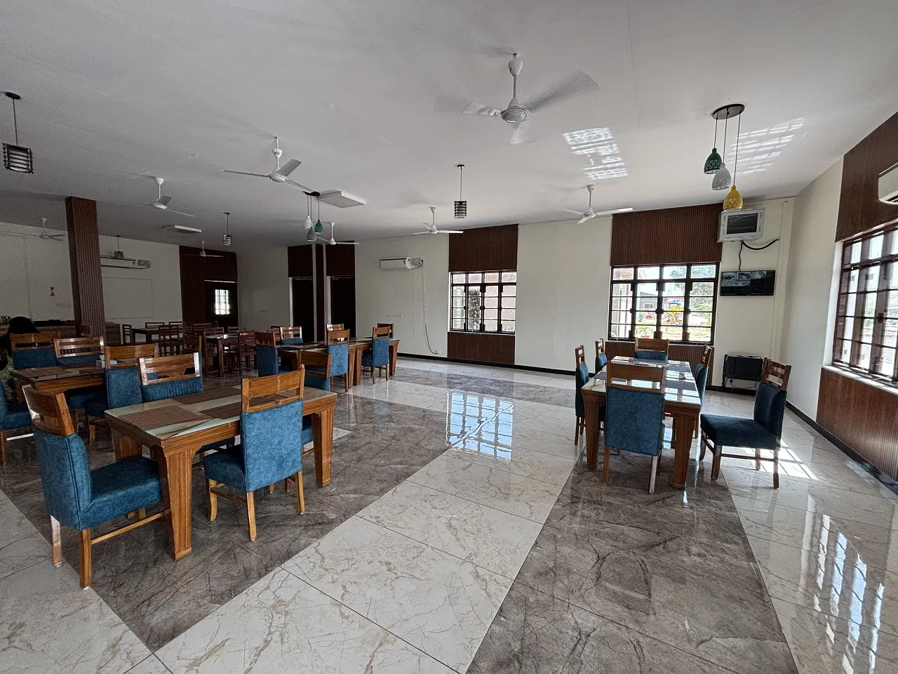 AC dining hall at Guru Kripa restaurant, Agolai, on the Bharatmala Expressway, with wooden tables and blue chairs